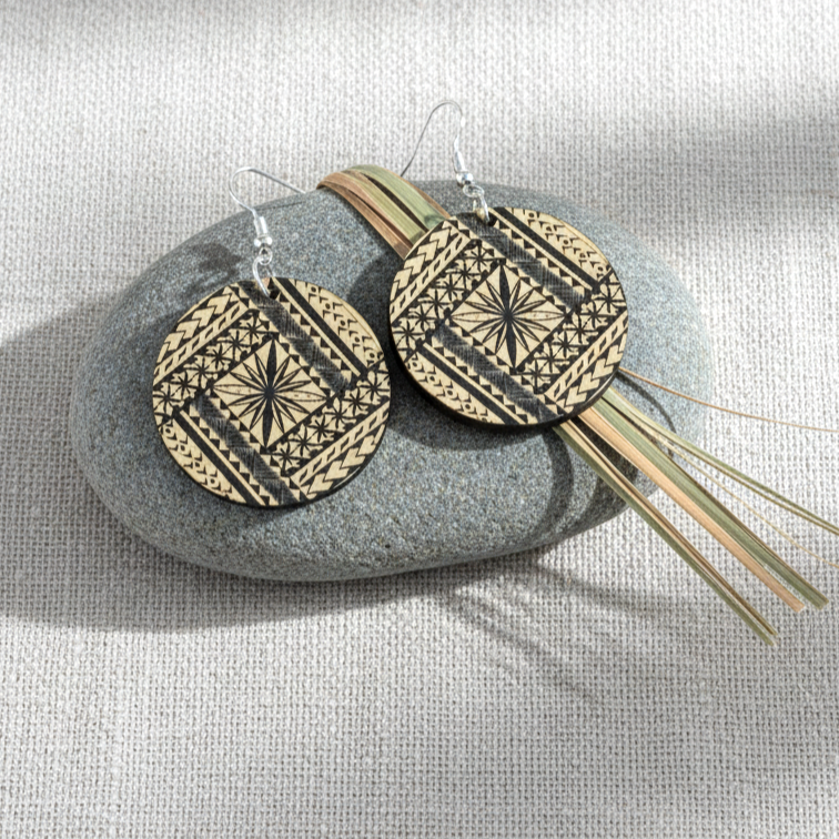 Samoan Round earrings styled on linen stone; brushed gold metallic acrylic pair.