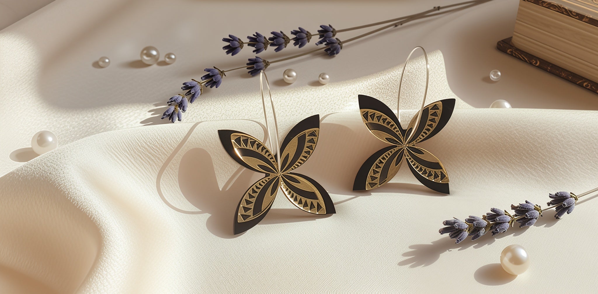 Lifestyle photo of black-and-gold frangipani spinner earrings on silver hoops, styled on ivory silk with lavender sprigs and scattered pearls.