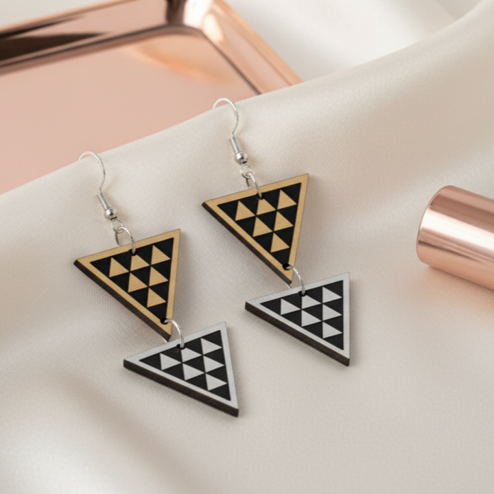 Tāniko Double earrings on silk; rose-gold mirror vanity tray and brushed metallic pair in gold and silver.