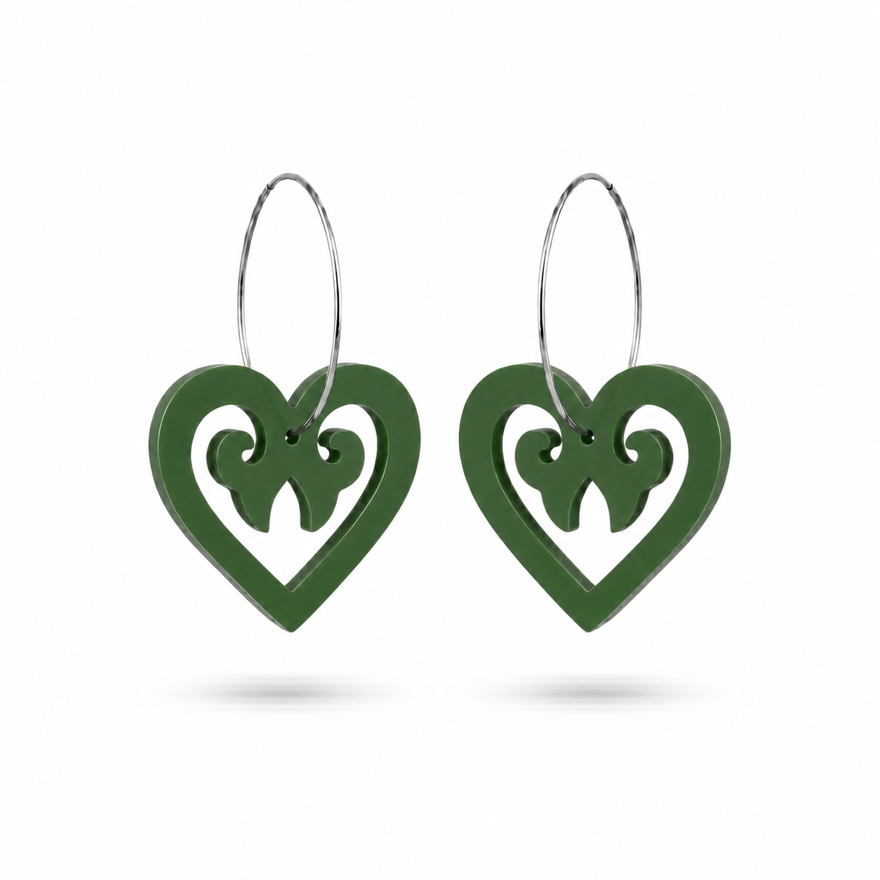 Pair of Aroha Heart Open earrings in fern-green Pounamu Satin Acrylic, with open-heart koru cutouts and large silver-coloured hoops.