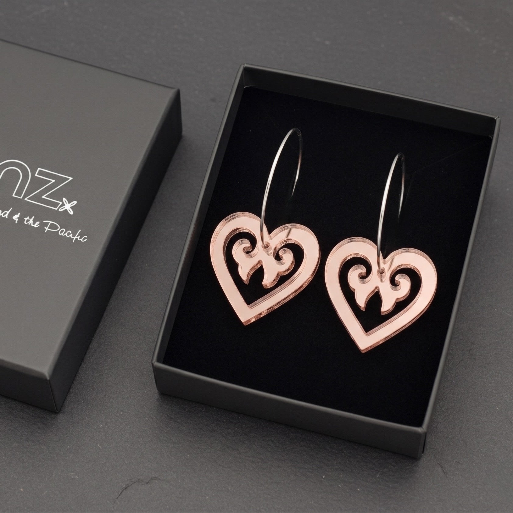 Aroha Heart Open earrings in rose-gold mirror, open heart with koru scrollwork, in SONZ gift box.