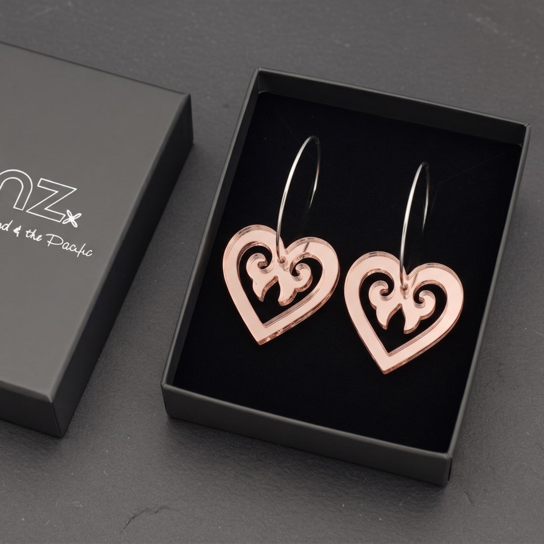Aroha Heart Open earrings in rose-gold mirror, open heart with koru scrollwork, in SONZ gift box.
