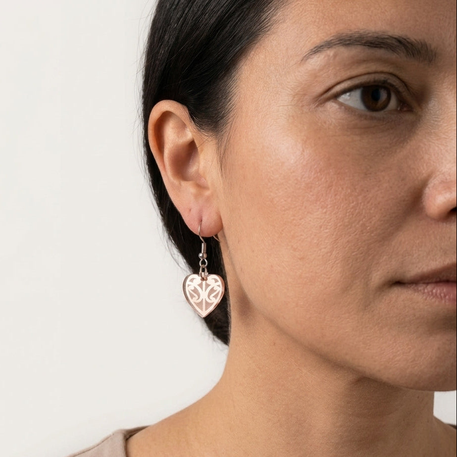 Close-up of a woman wearing a heart-shaped earring with a white background